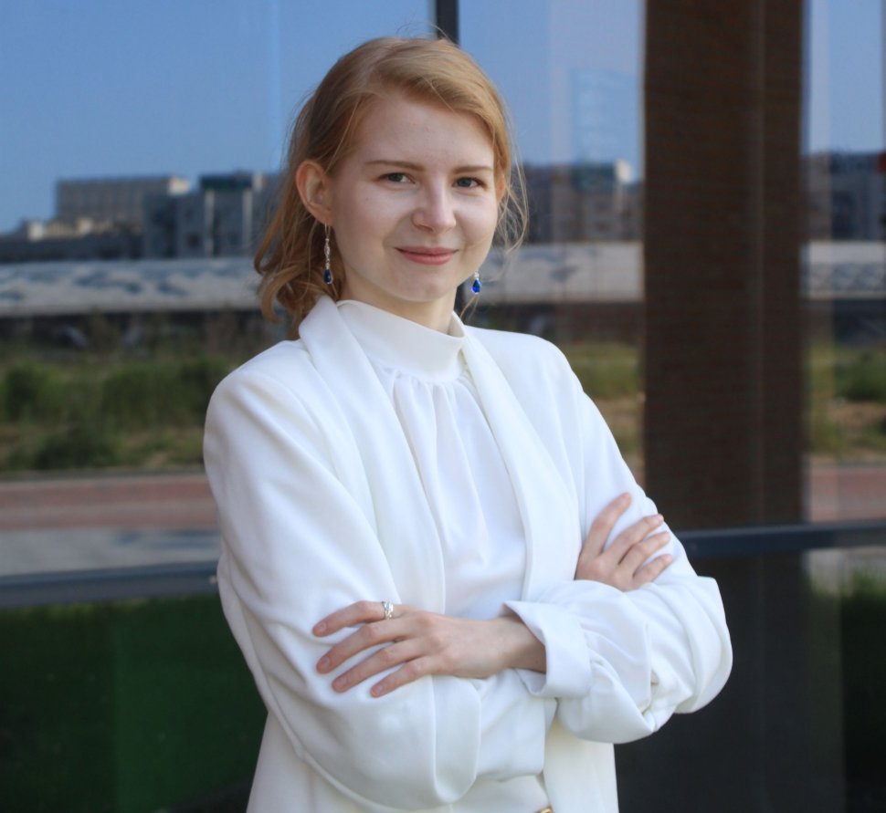 Photo of a doctoral student against the background of a glass building 