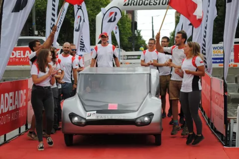 A group of students from the Lodz Solar Team standing next to the vehicle at the finish line of the race