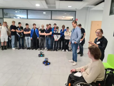 Grupa uczniów z prowadzącą pokaz robotów mobilnych na korytarzu Fabryki Inżynierów XXI w.
