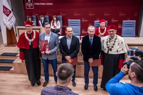 Grupa pracowników z rektorem podczas uroczystego Senatu odbierająca nagrodę